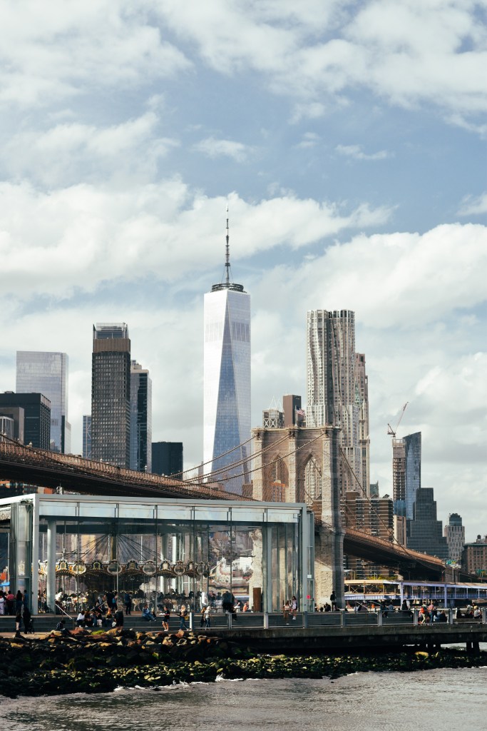 Brooklyn Bridge, One World Trade Center building and Jane's carousal from Pebble Beach in New York